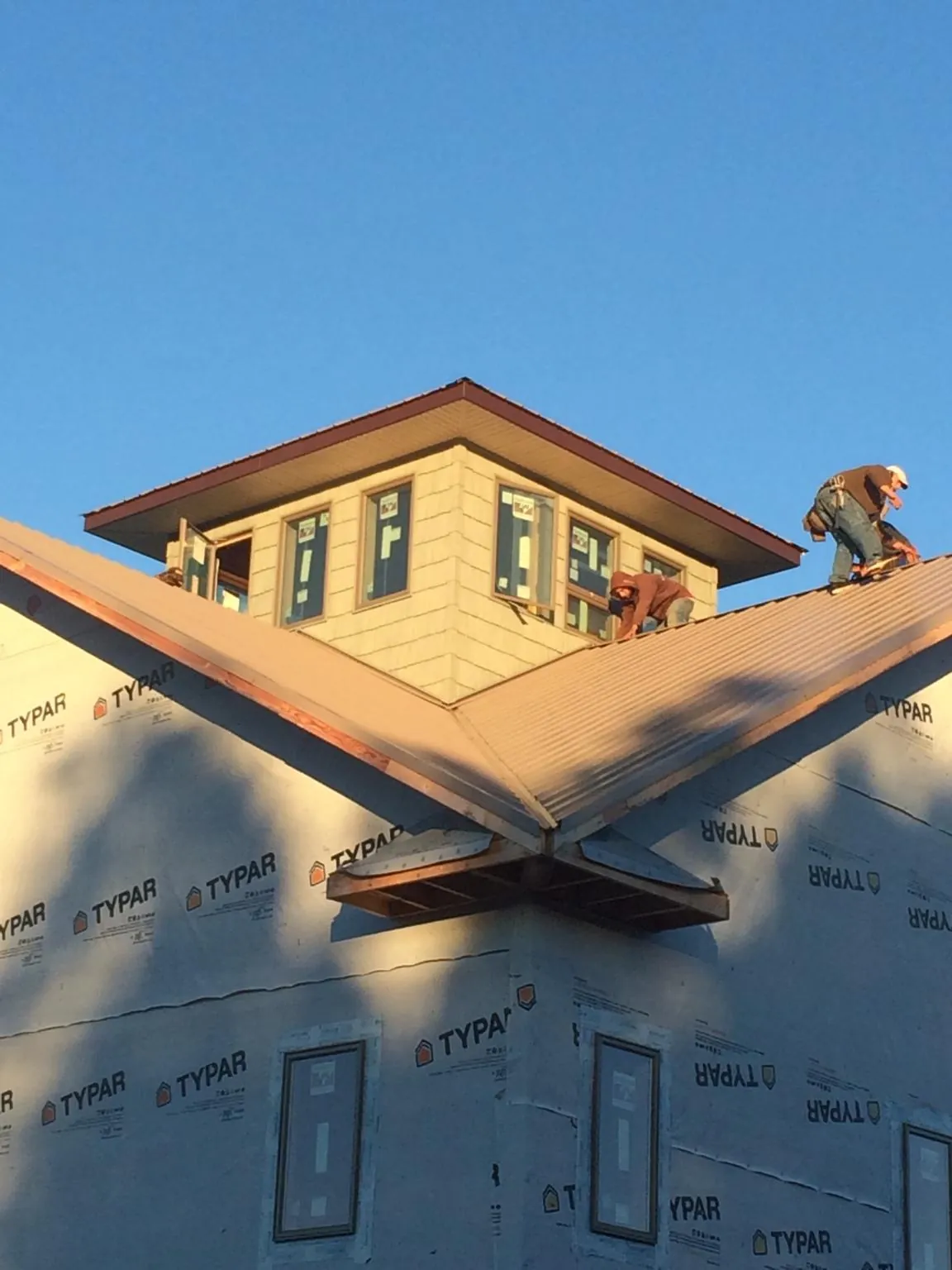 Roofers working around a rooftop cupola on a new metal roof at sunset — Roof Waterproofing in Evergreen by Roofing Brothers